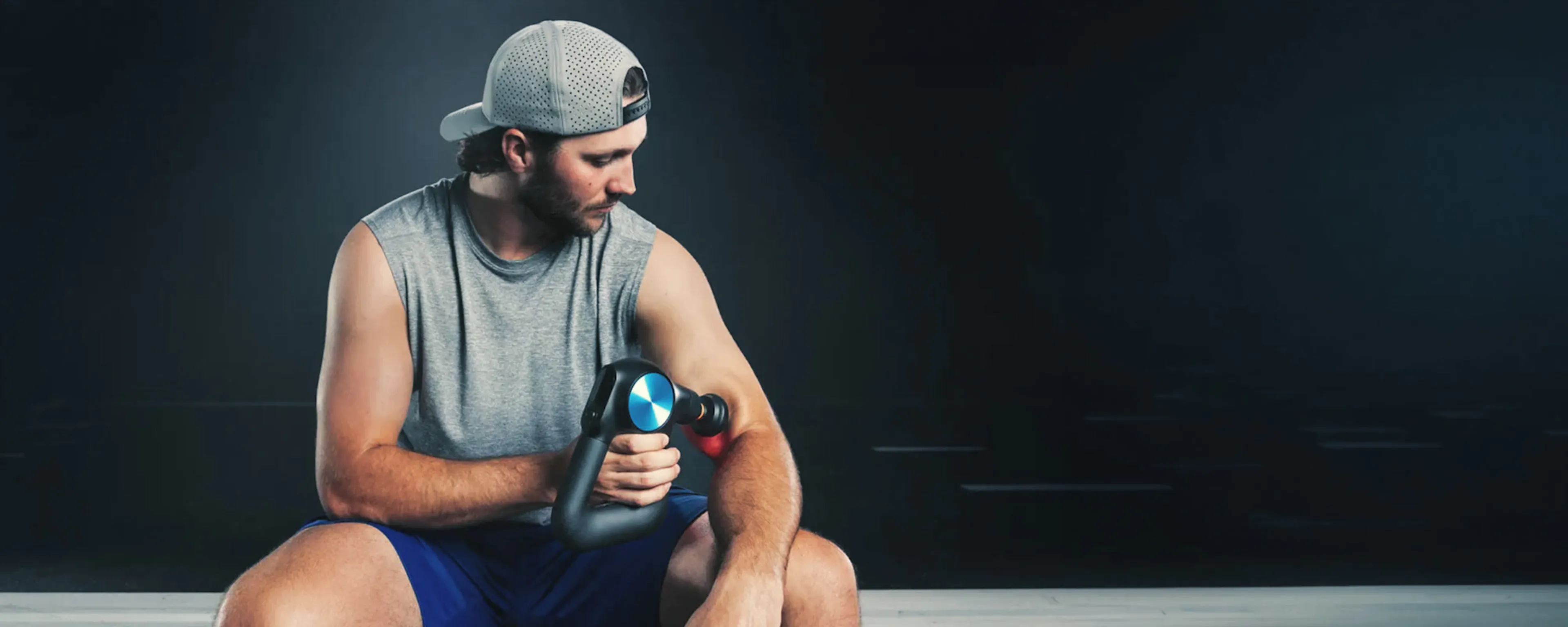 Athlete using a Theragun percussive massage device after training
