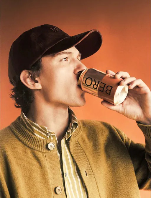 Man drinking a BERO non-alcoholic beer against an orange backdrop