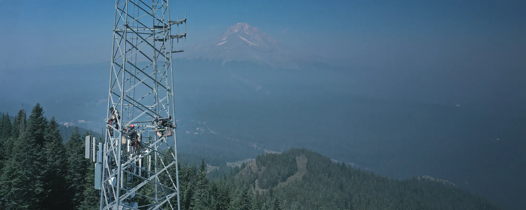 Communications tower on a ridgeline with mountains behind — Day Wireless