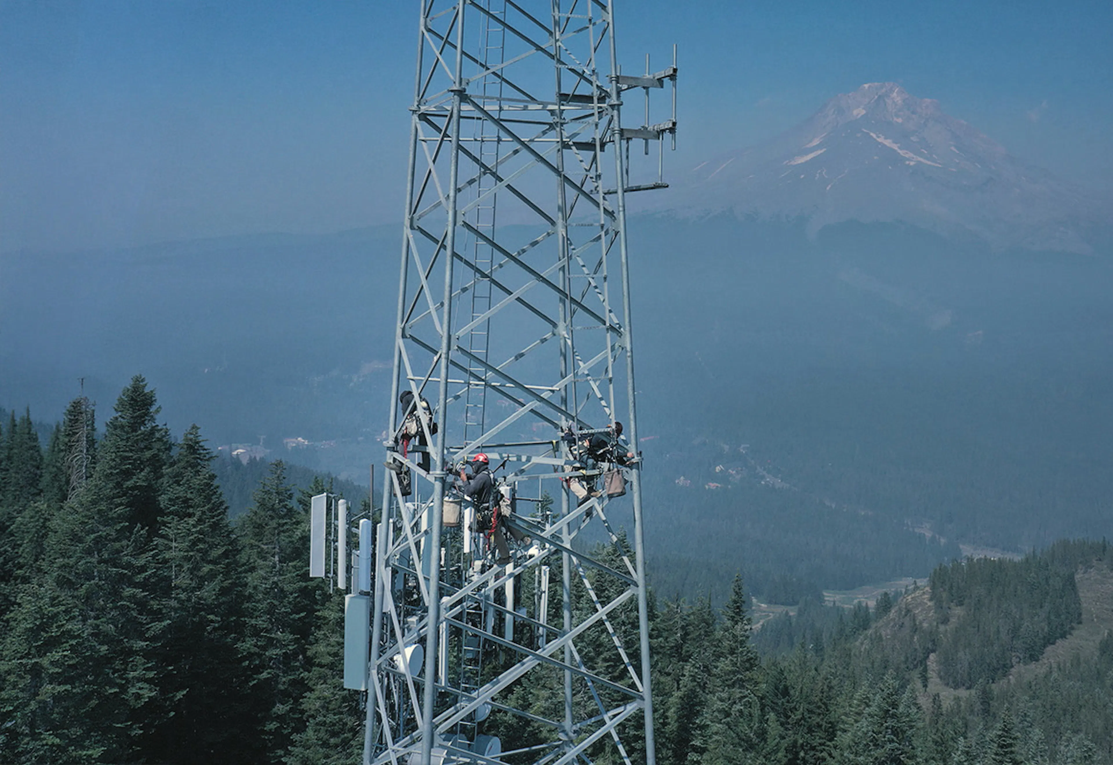 Communications tower on a ridgeline with mountains behind — Day Wireless