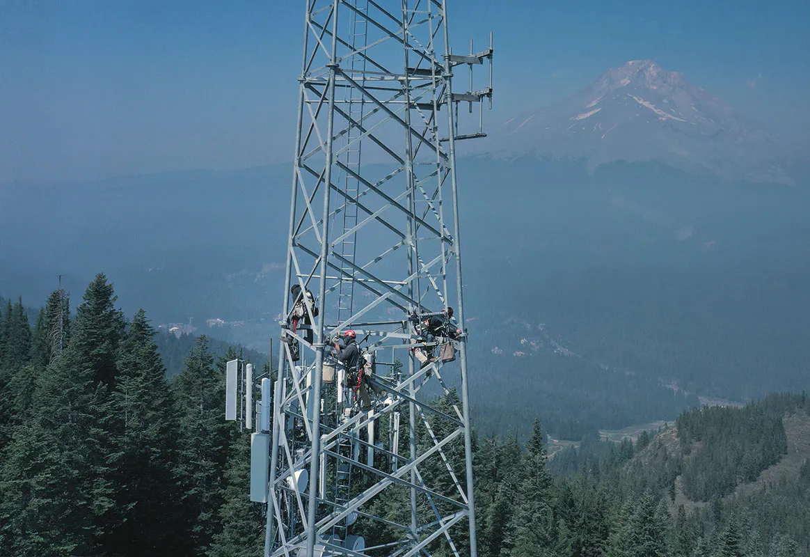 Communications tower on a ridgeline with mountains behind — Day Wireless