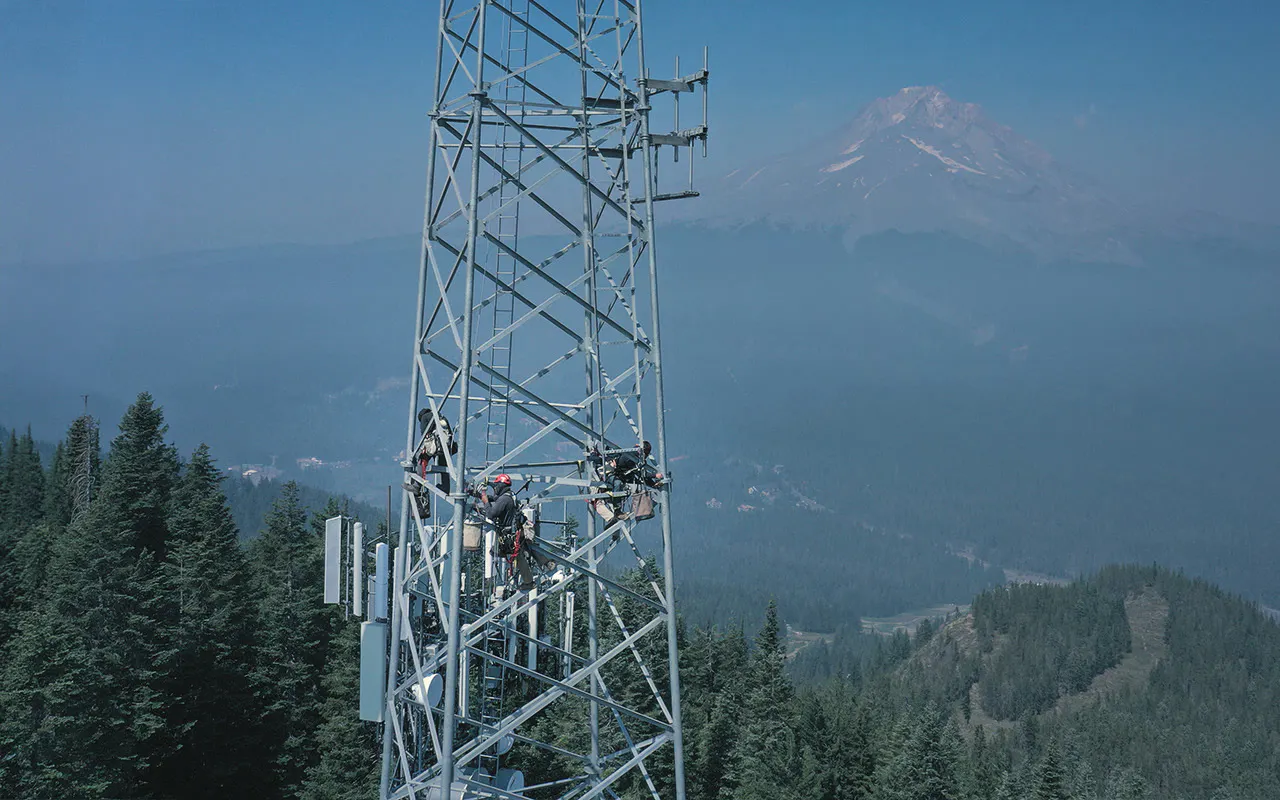 Communications tower on a ridgeline with mountains behind — Day Wireless