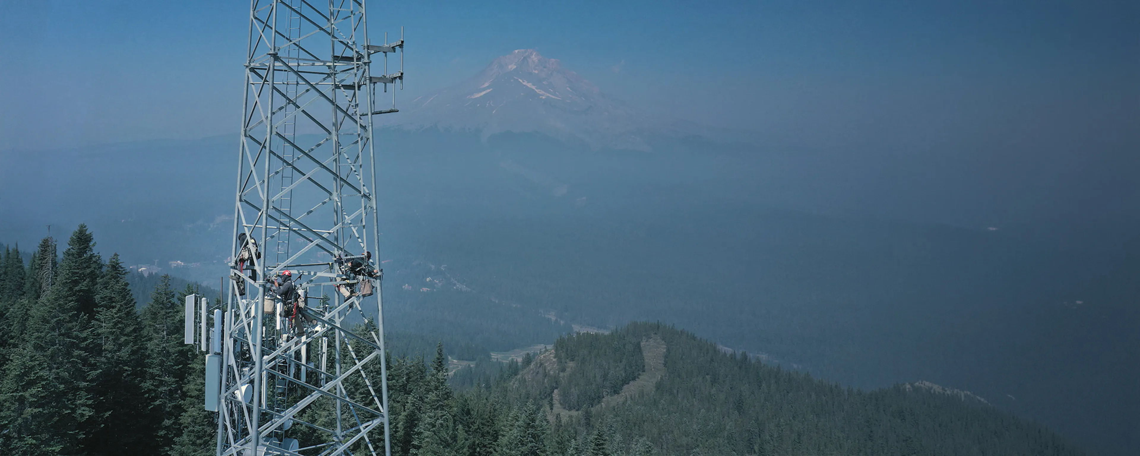 Communications tower on a ridgeline with mountains behind — Day Wireless