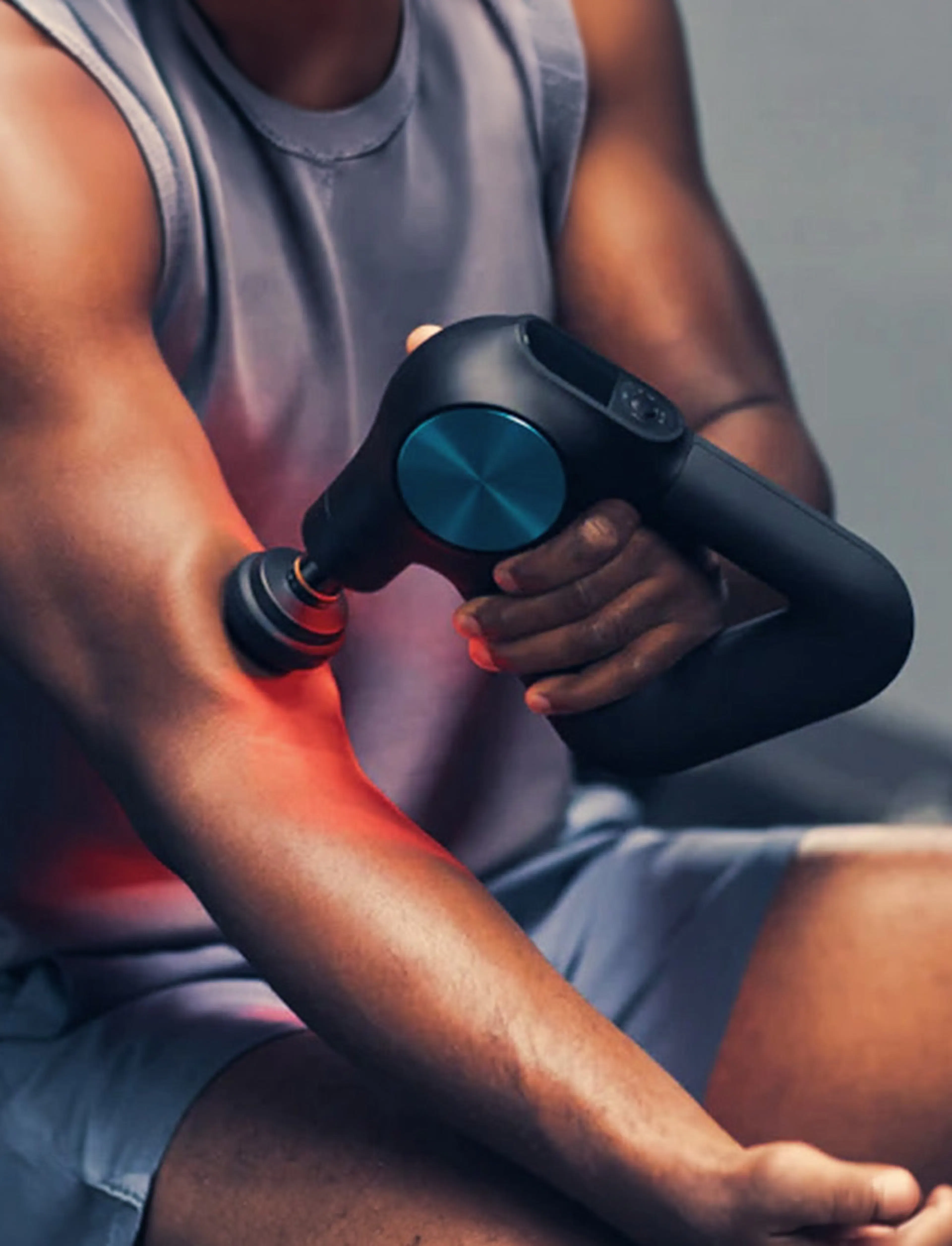 Close-up of a Theragun percussive therapy device used on a forearm