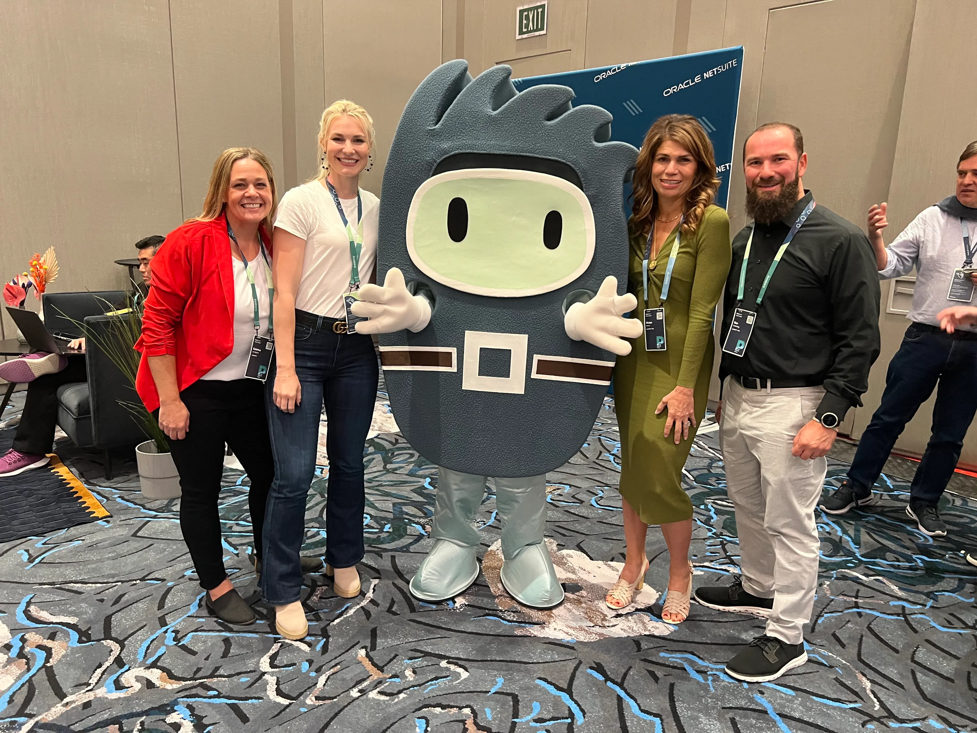 Luxent team members posing with the NetSuite mascot at the Oracle NetSuite booth