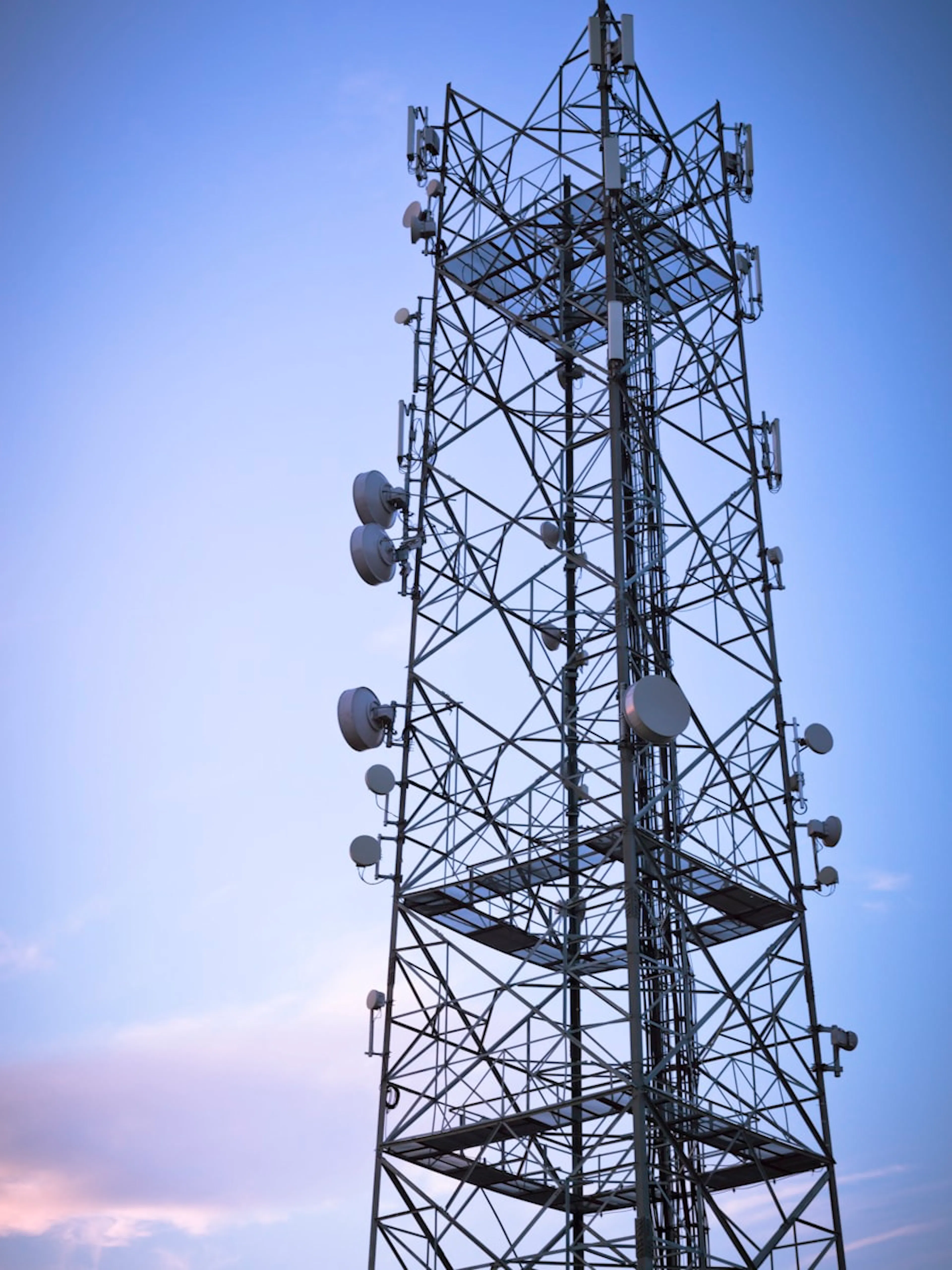 Lattice communications tower against an evening sky — P&R Communications