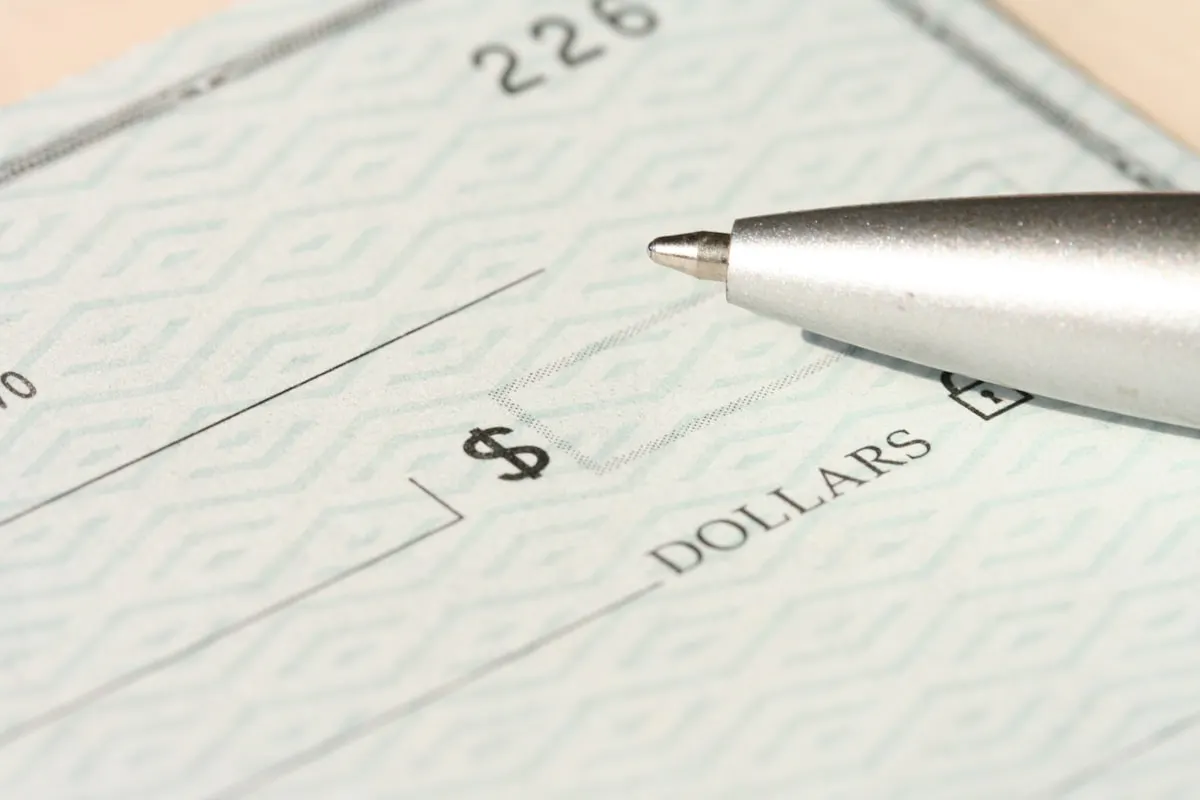 Silver pen resting on the amount line of a paper check