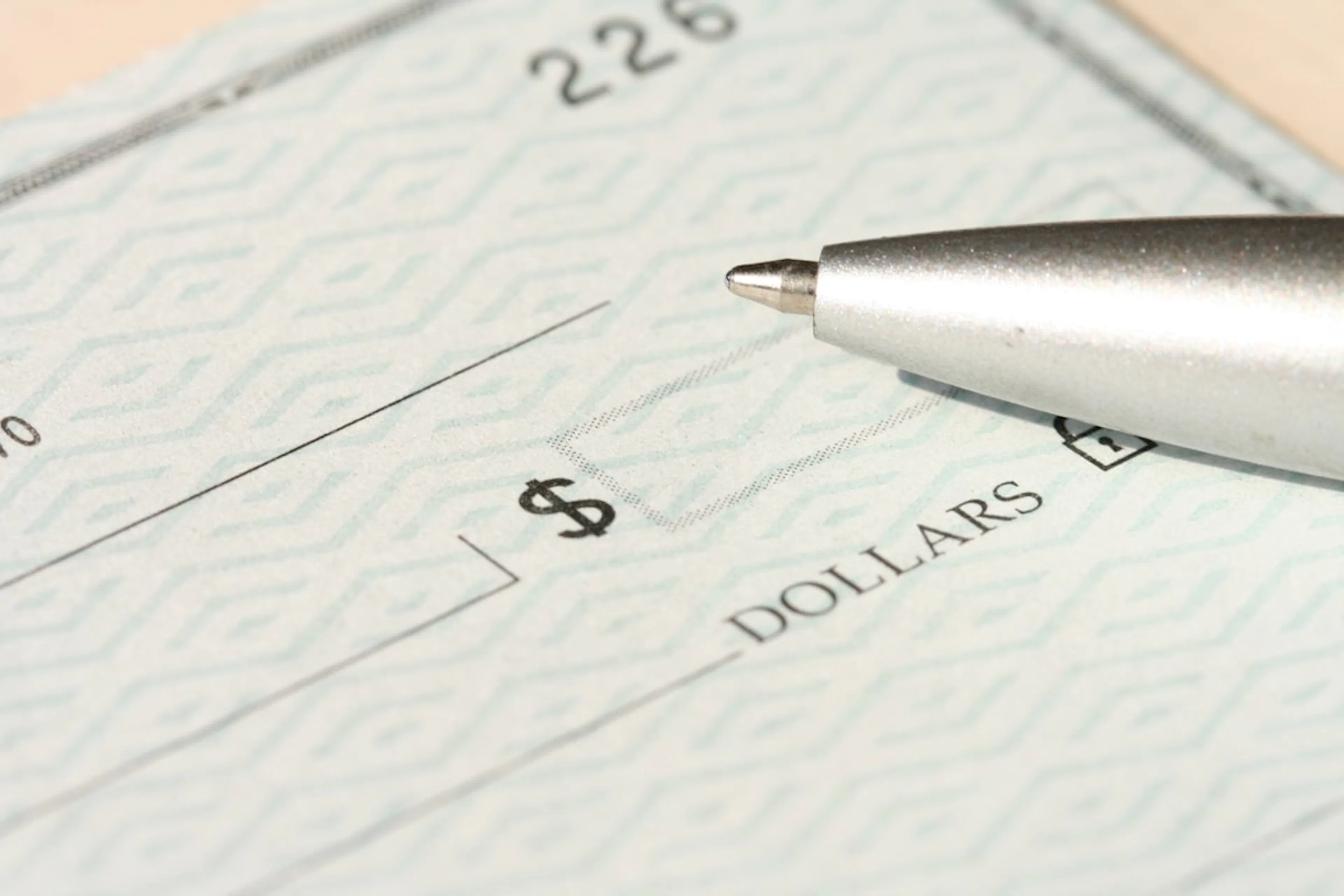 Silver pen resting on the amount line of a paper check