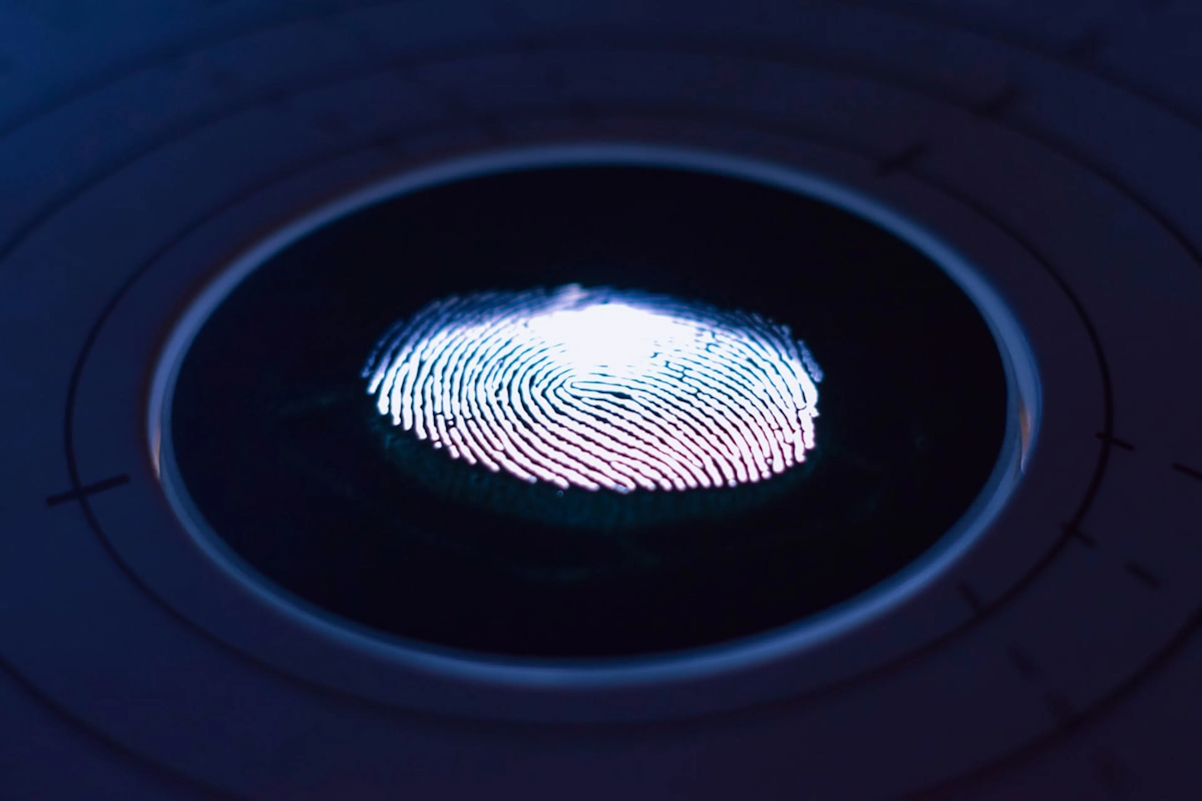 Glowing fingerprint lit up on a dark circular sensor