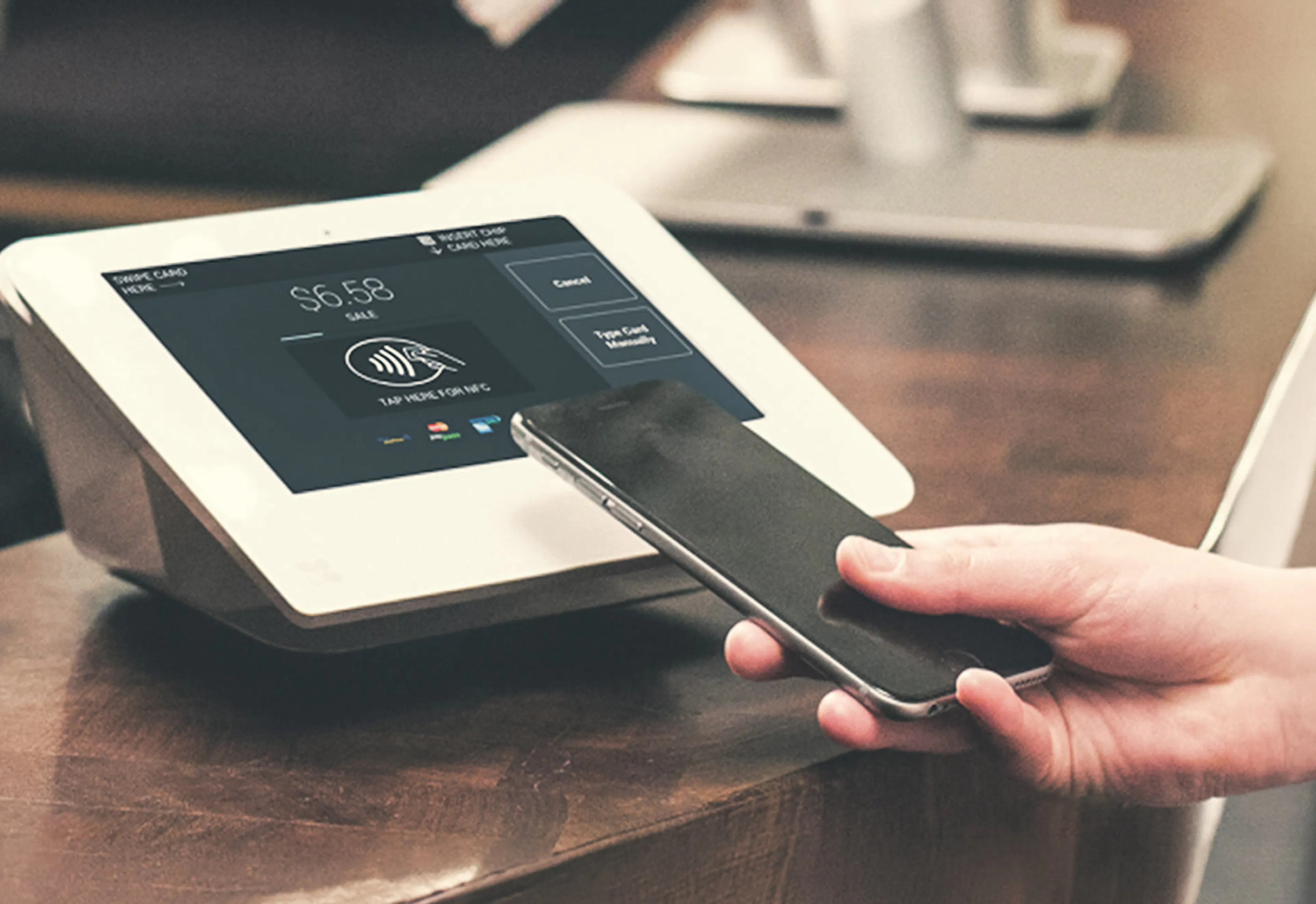 Customer tapping a phone to pay at a Brilliant POS tablet terminal