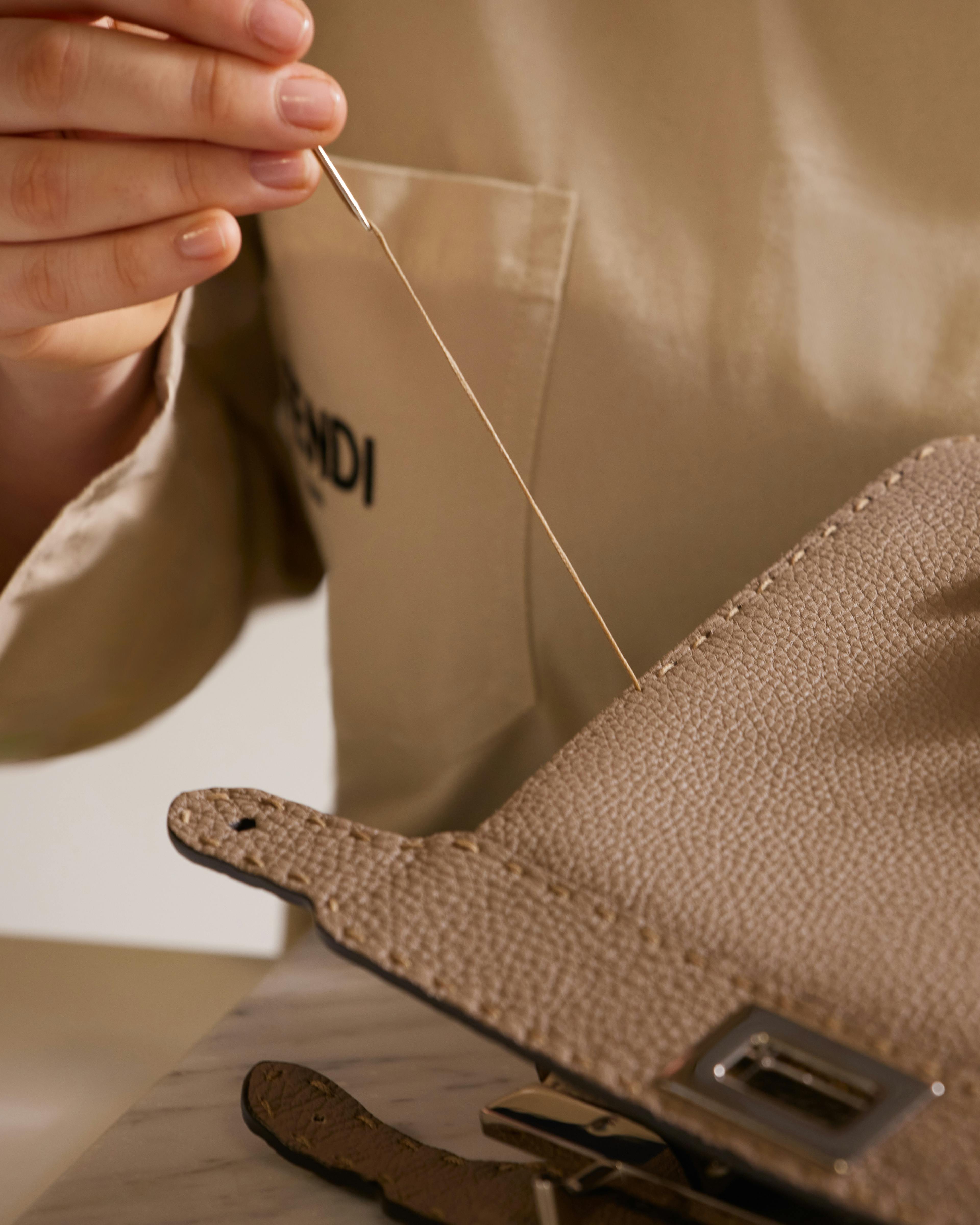 A Fendi leather artisan fixing the details of a Fendi Mini Peekaboo bag in exotics  © Courtesy of Fendi