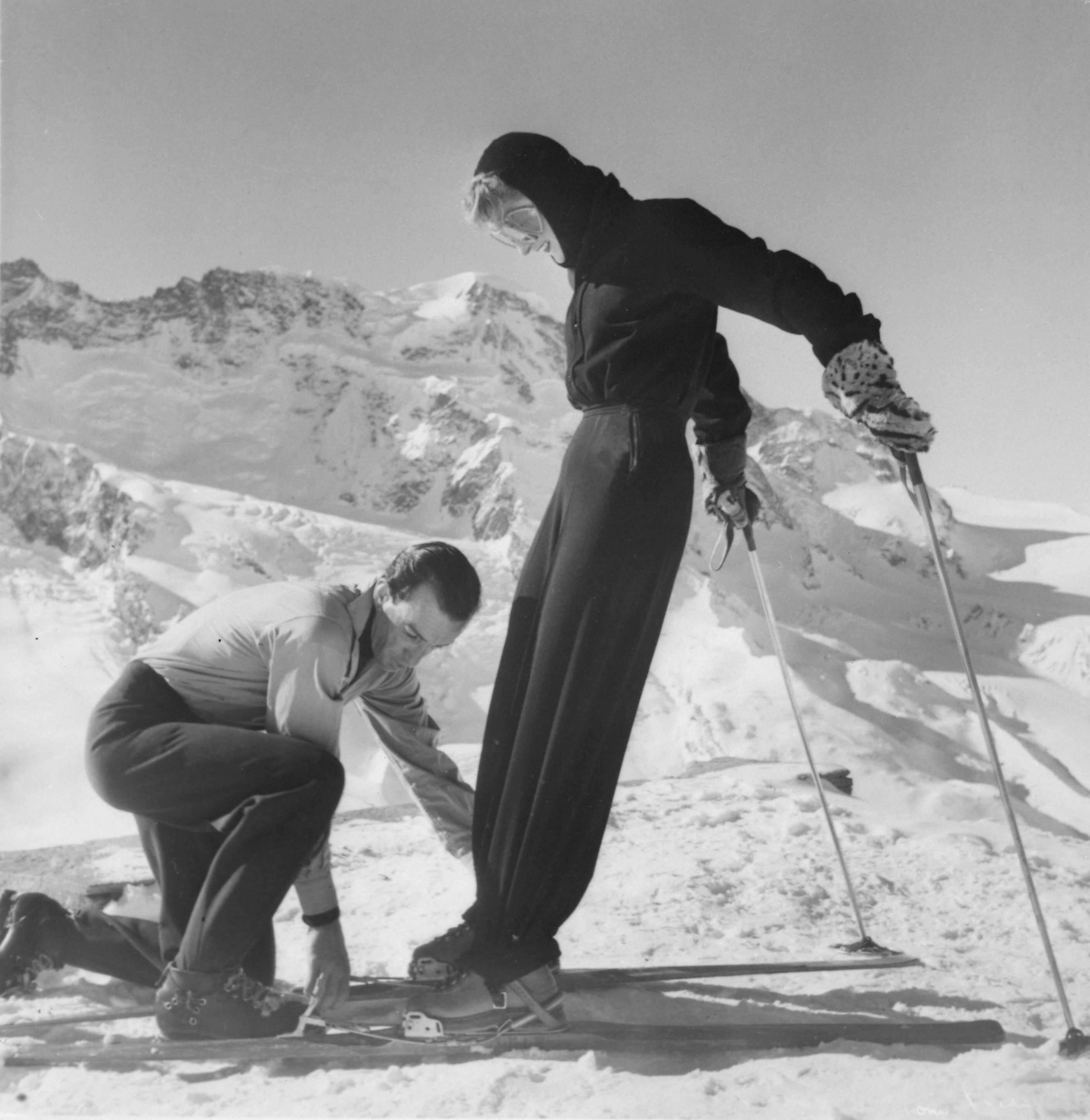 Marquis Emilio Pucci fastens a ski for Mrs Poppi de Salis, who wears a Pucci ski outfit; Zermatt, 1947. Harper’s Bazaar, December 1948. © Emilio Pucci