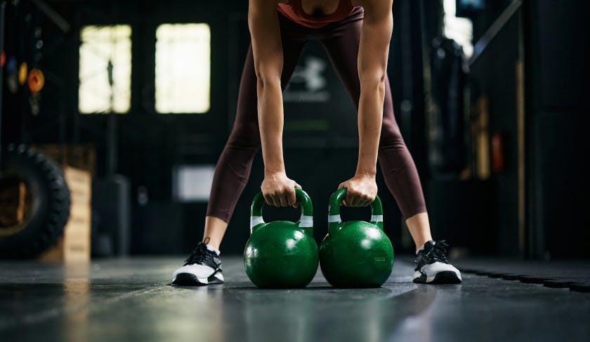 Девушка с гирями в фитнес зале