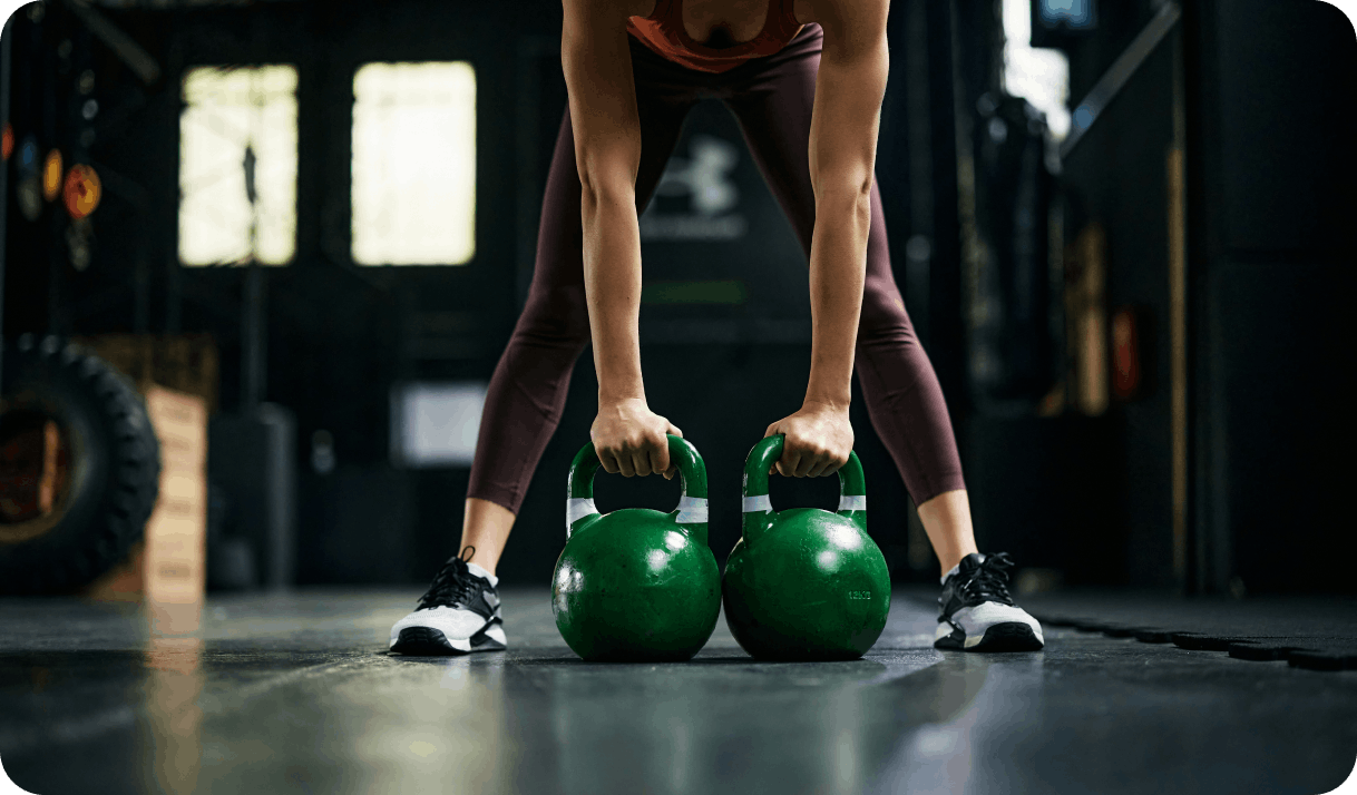 Девушка тренируется в клубе с гирями