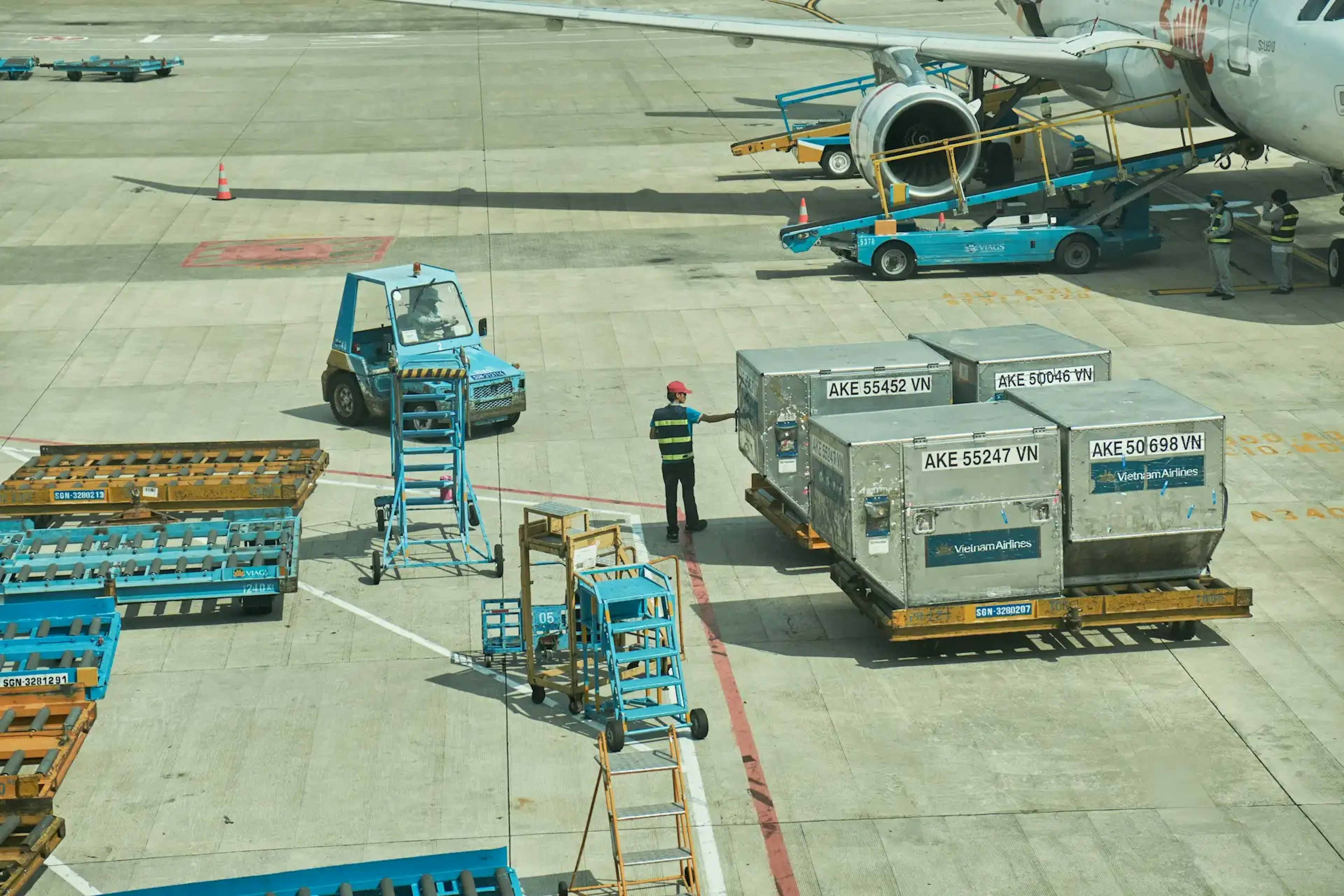 man standing next to airplane cargo on tarmac