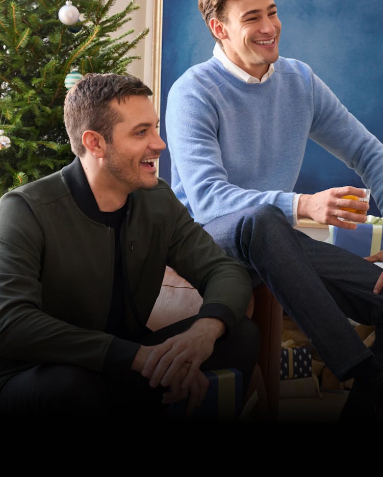 2 men wearing Mack Weldon attire, sitting on a couch in front of a holiday tree