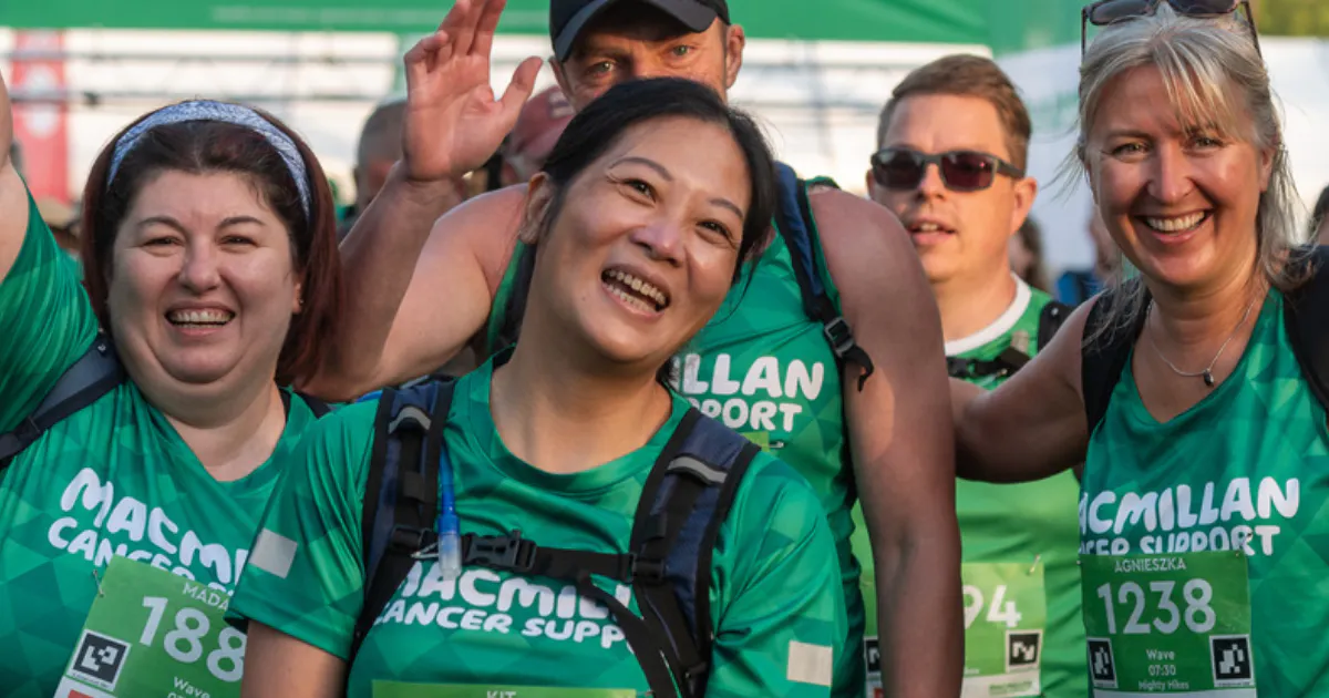 Participants in green Macmillan Cancer Support tops wave during a Mighty Hike event.