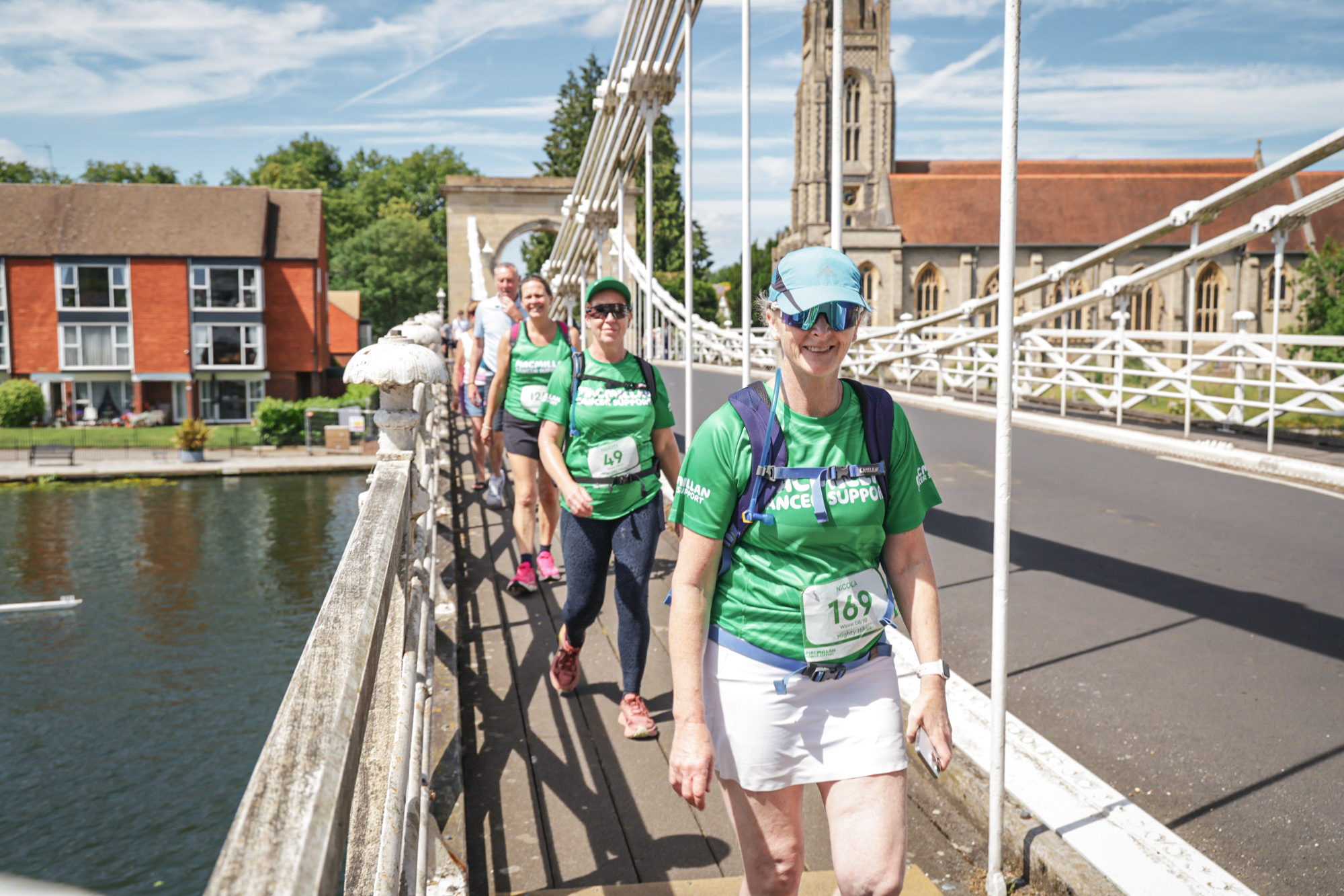 A group of Mighty Hikers walk along a suspension bridge over the River Thames.