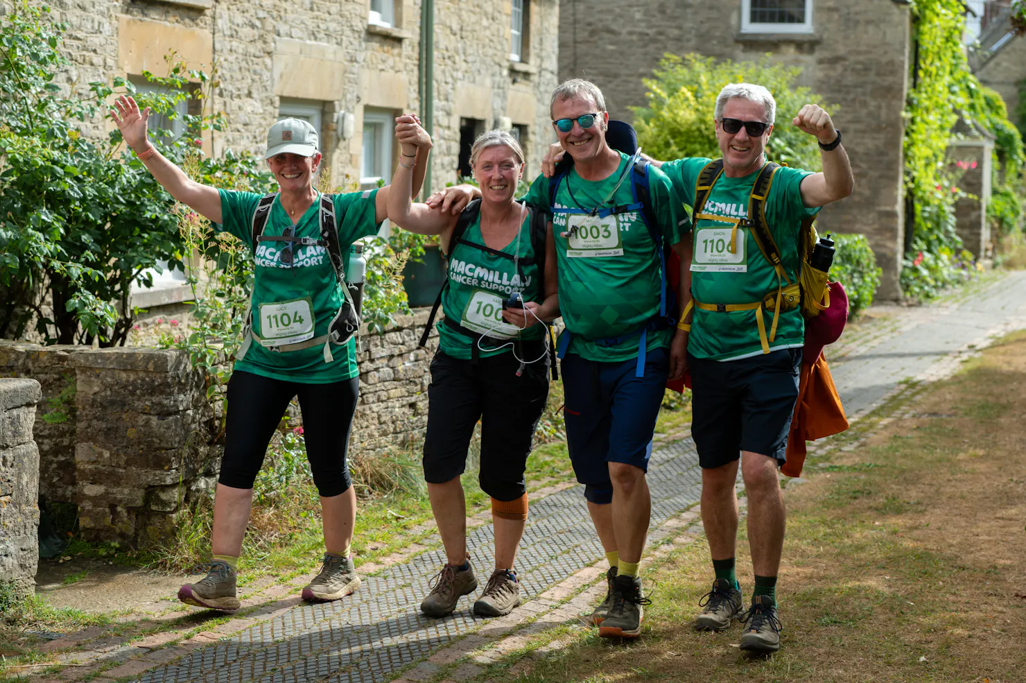 A group of hikers raising their hands in the air and smiling.