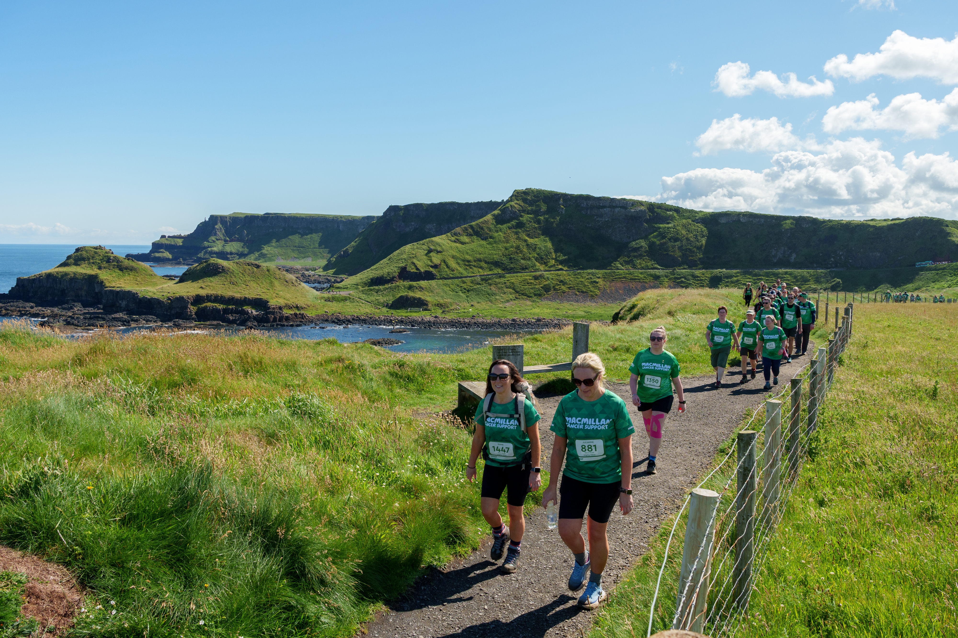 A coastal shot showing a group of hikers in green tops.