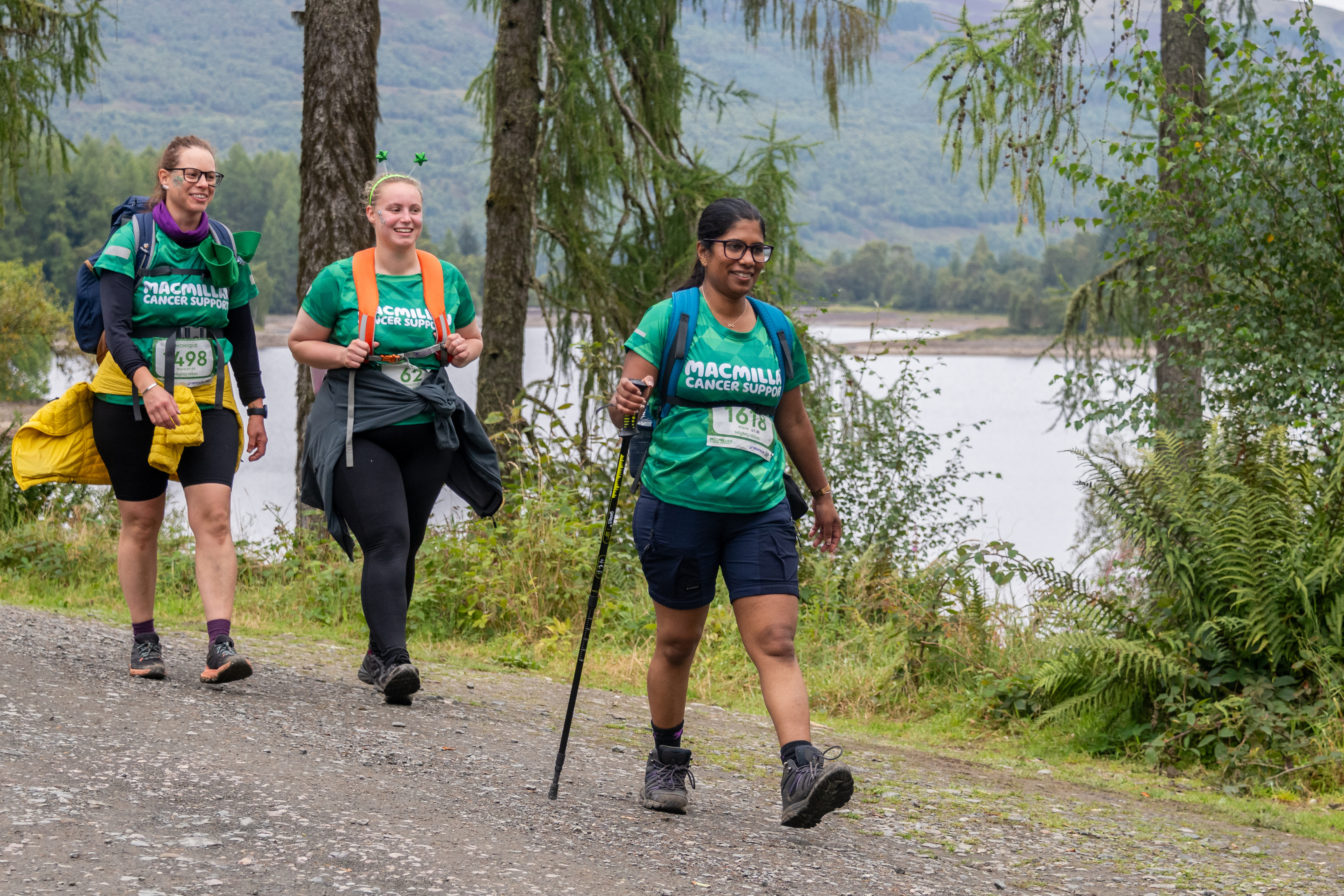 A group of smiling women walking whilst wearing their green Macmillan t-shirts.