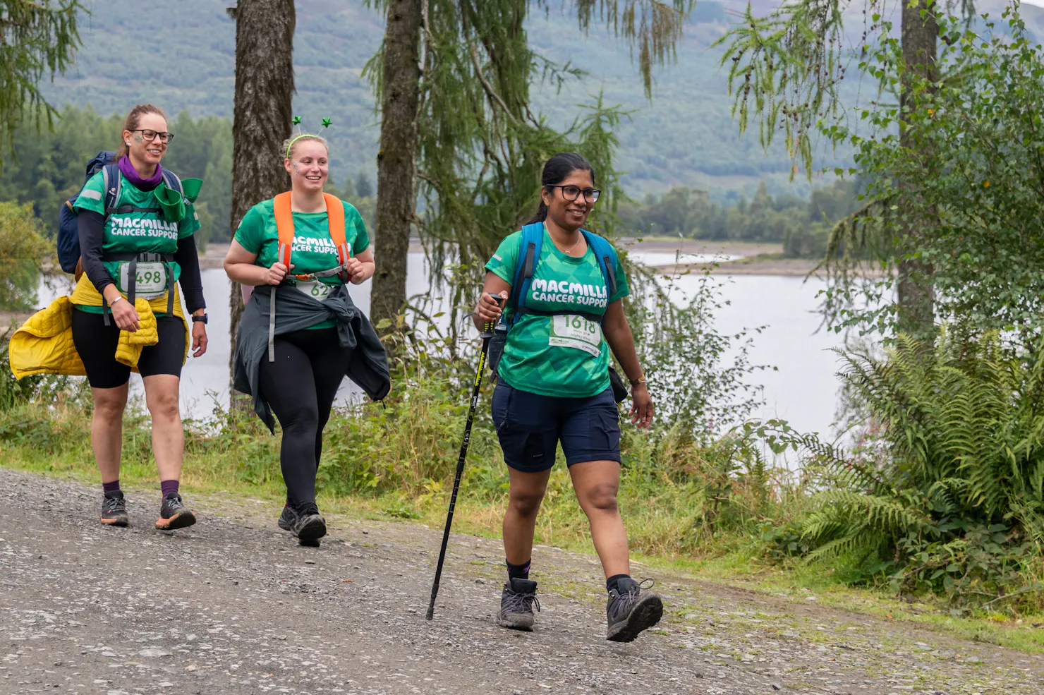 A group of smiling women walking whilst wearing their green Macmillan t-shirts.