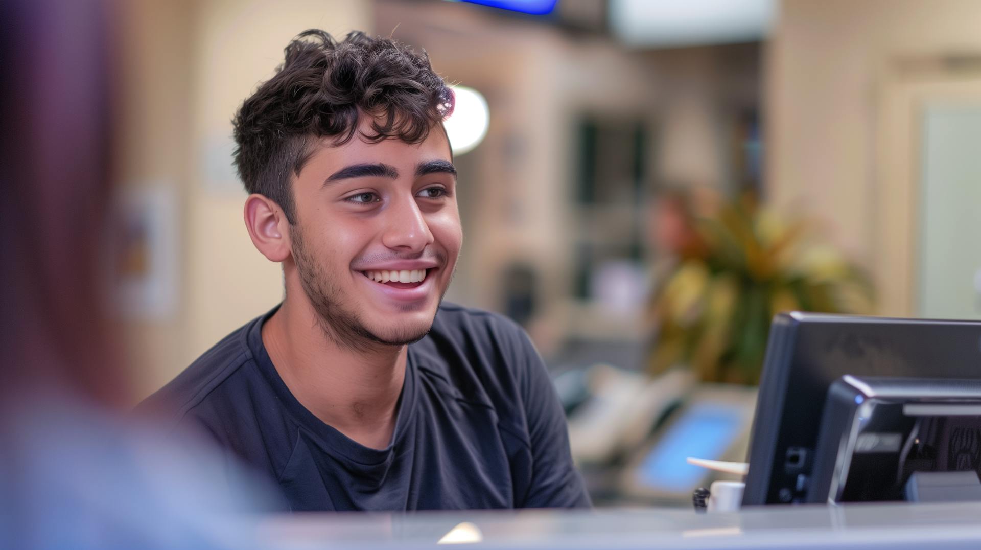 A young male apprentice sitting at a reception desk.