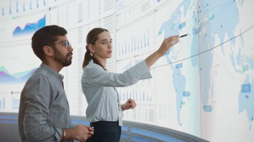 Man and woman looking at a world map on a large screen