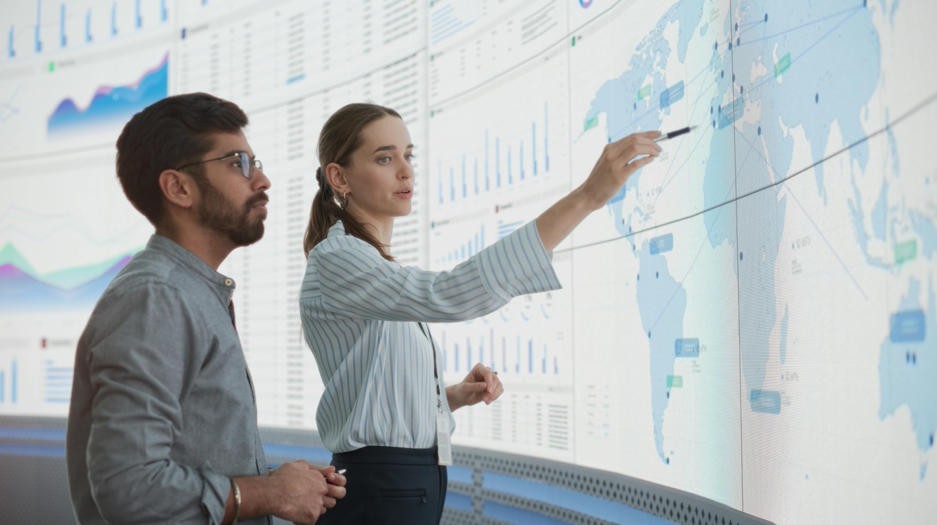 Man and woman looking at a world map on a large screen