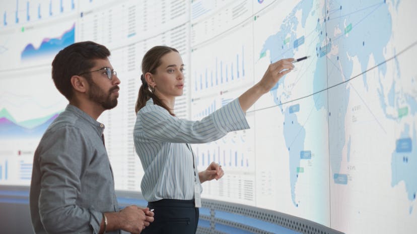 Man and woman looking at a world map on a large screen