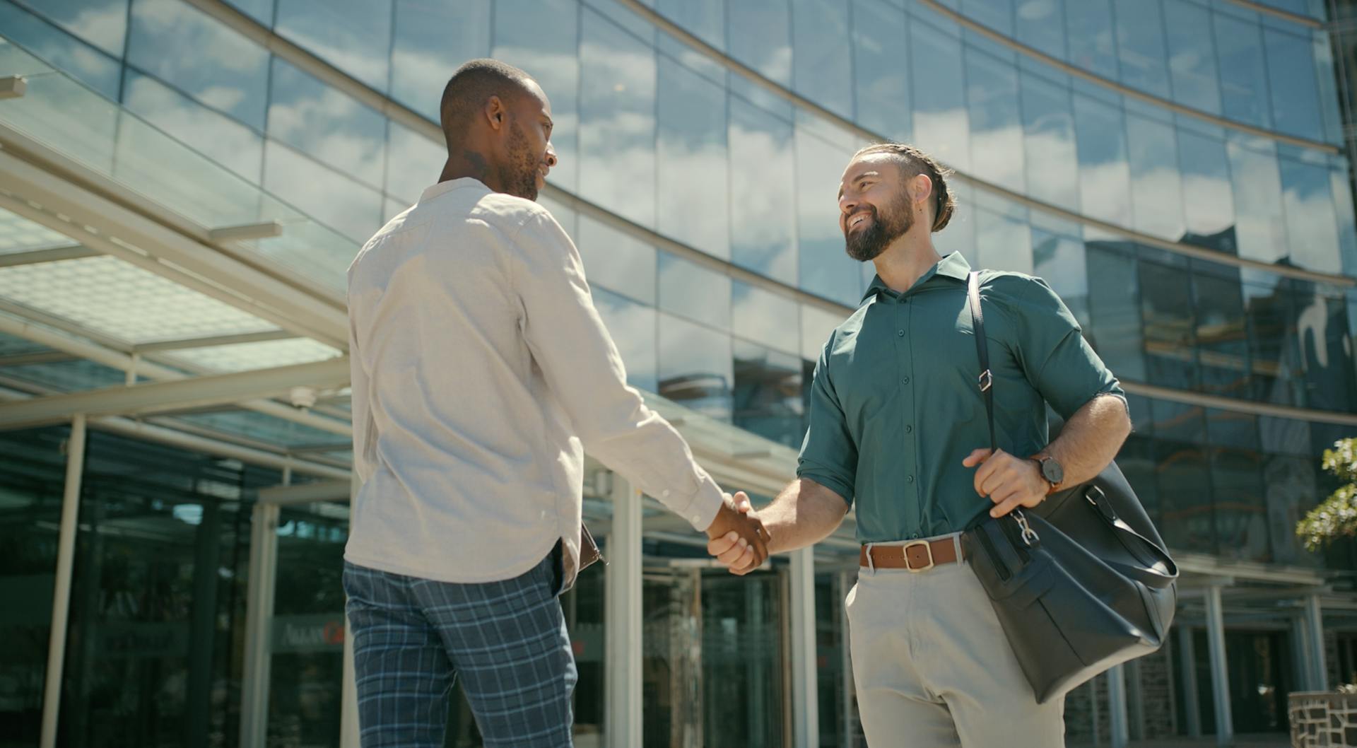 Two men shaking hands in front of a facility