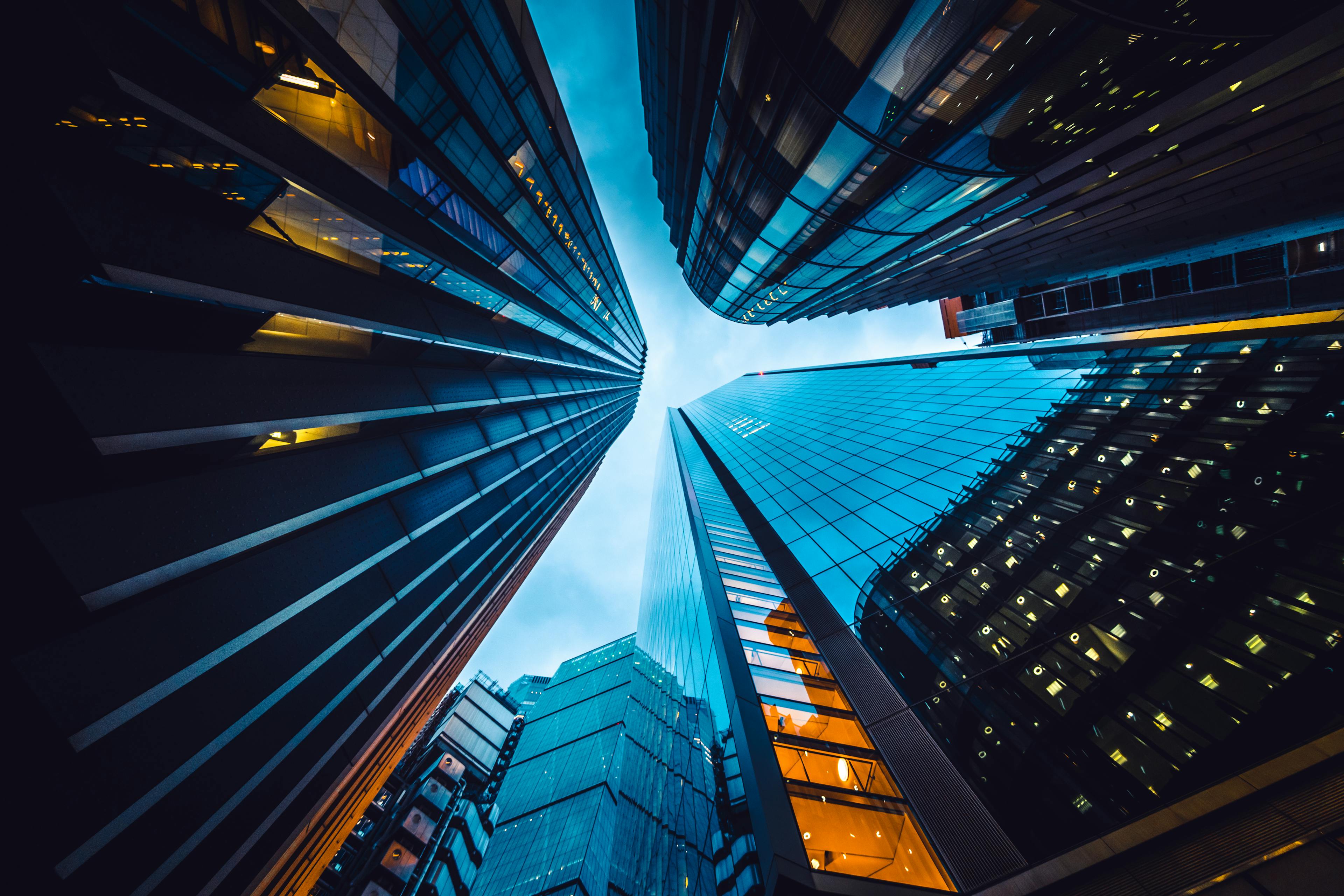 Buildings from a low angle and blue sky above reflecting in the windows