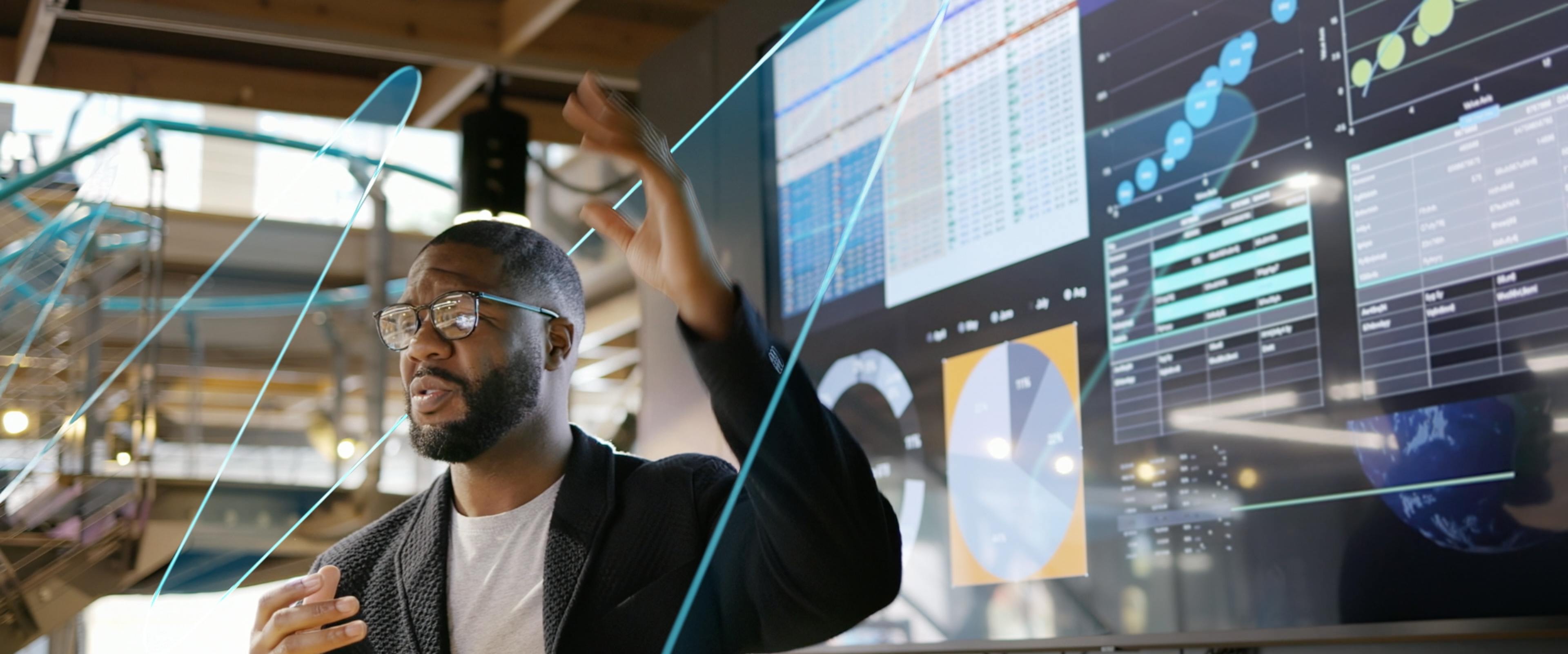 A man presenting on screen with The Macro Wave graphic moving by him
