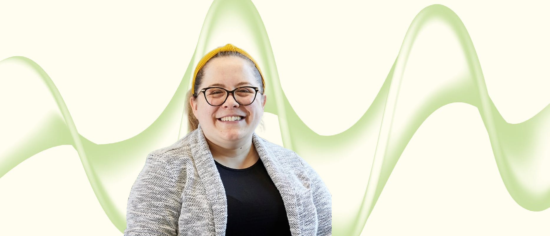 image of a woman with blonde hair and glasses in a grey jacket on a cream and green background