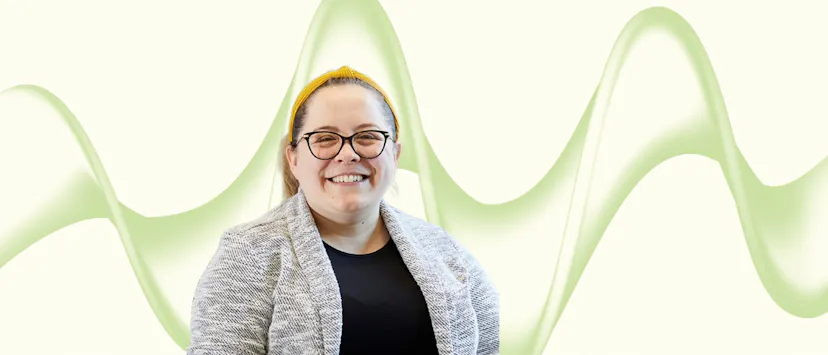image of a woman with blonde hair and glasses in a grey jacket on a cream and green background