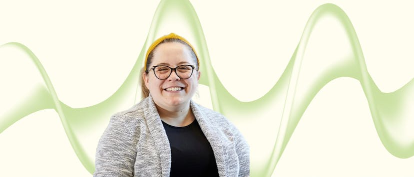 image of a woman with blonde hair and glasses in a grey jacket on a cream and green background