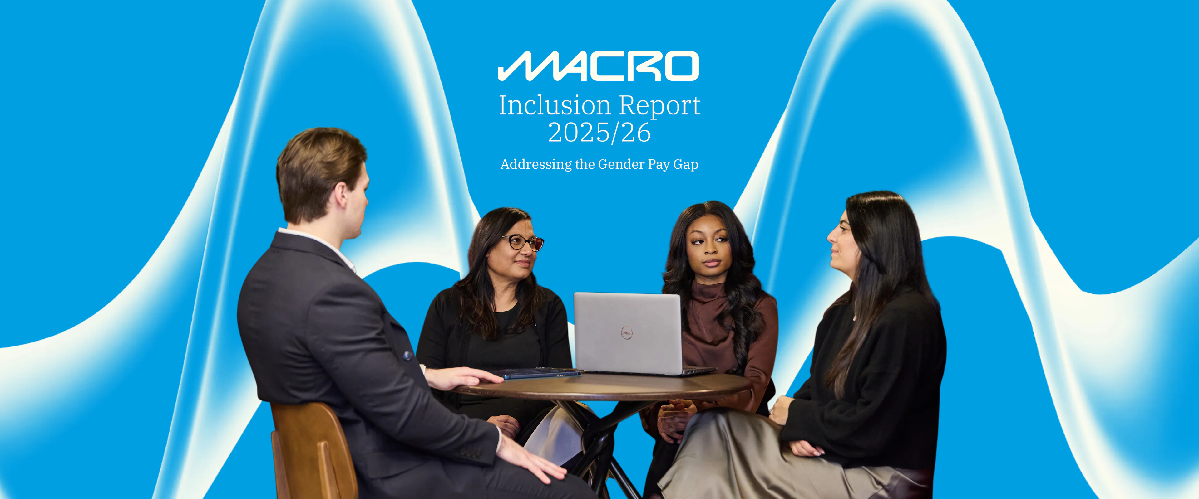 three women and a man at a table with a laptop on a blue background