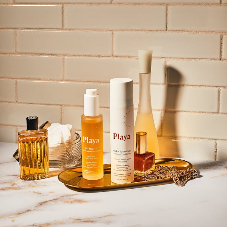 Image of bottle of Playa Ritual Hair Oil and Endless Summer Spray hair texture on vanity with perfumes.