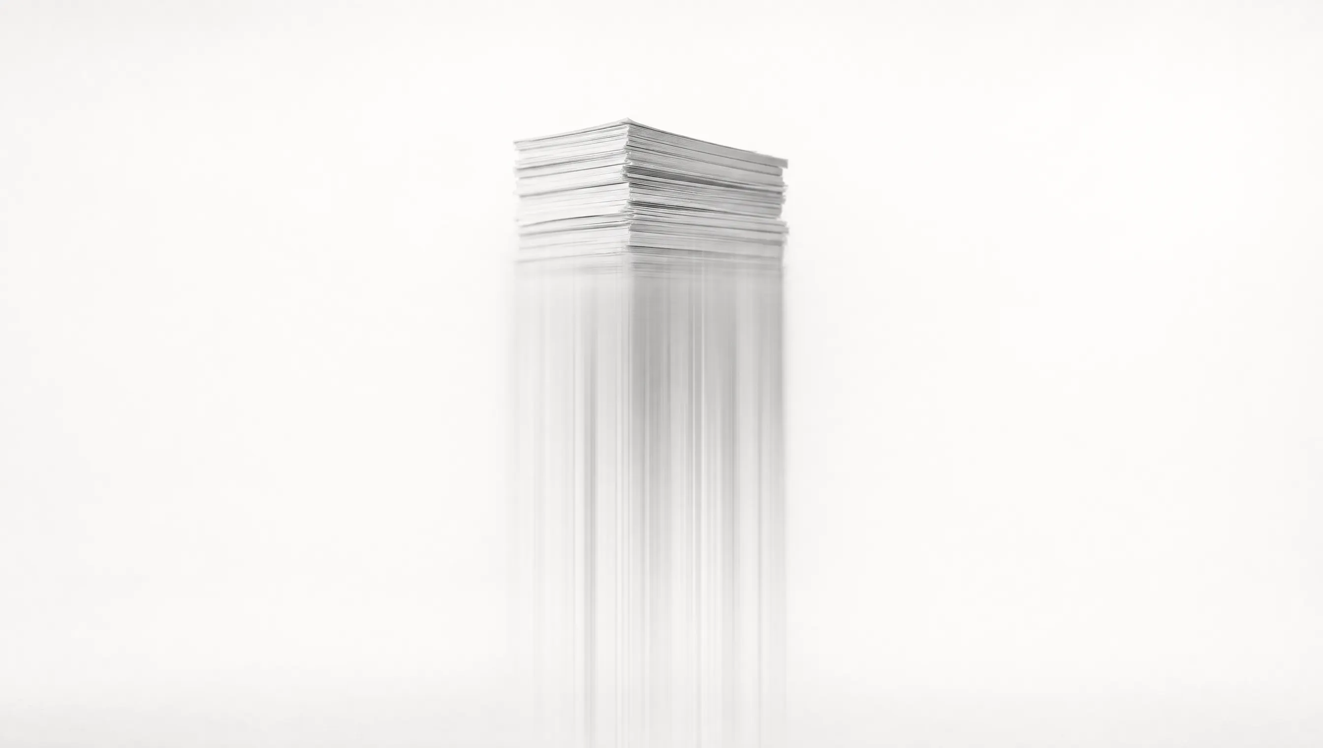 Pila di documenti di carta su fondo bianco: la parte alta è nitida, la metà bassa si dissolve in scie verticali di luce