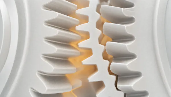 Macro di denti di ingranaggio in materiale bianco opaco: a sinistra si incastrano, a destra restano disallineati, con un bagliore ambra al centro