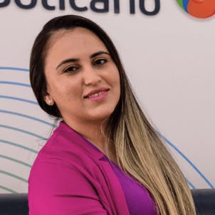 Mulher de cabelo escuro e longo com mechas claras nas pontas e maquiagem leve, sorrindo.