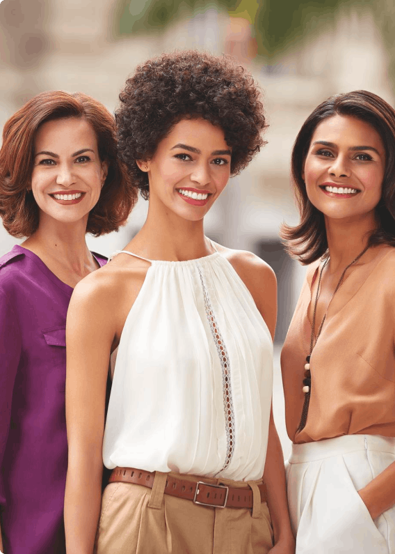 Três revendedoras da marca sorrindo e fazendo pose com a mão no bolso da calça.