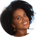 Mulher negra, de cabelo crespo, sorrindo.