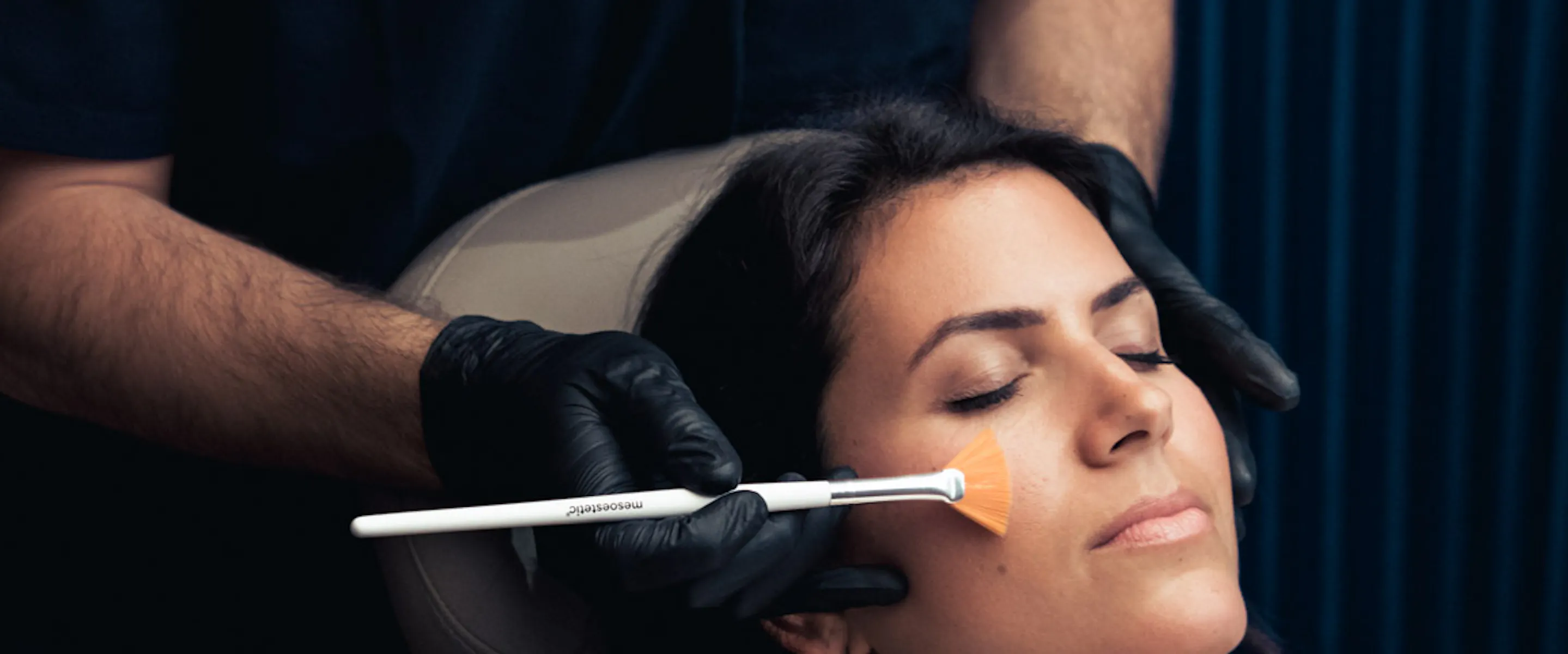 Médecin qui applique un peeling sur le visage d'une femme.