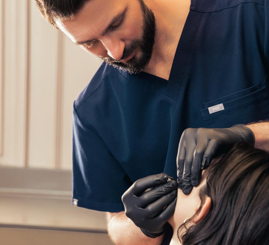 Praticien de chez Maison Yokō Lyon qui réalise des injections d'acide hyaluronique dans le visage d'une patiente.