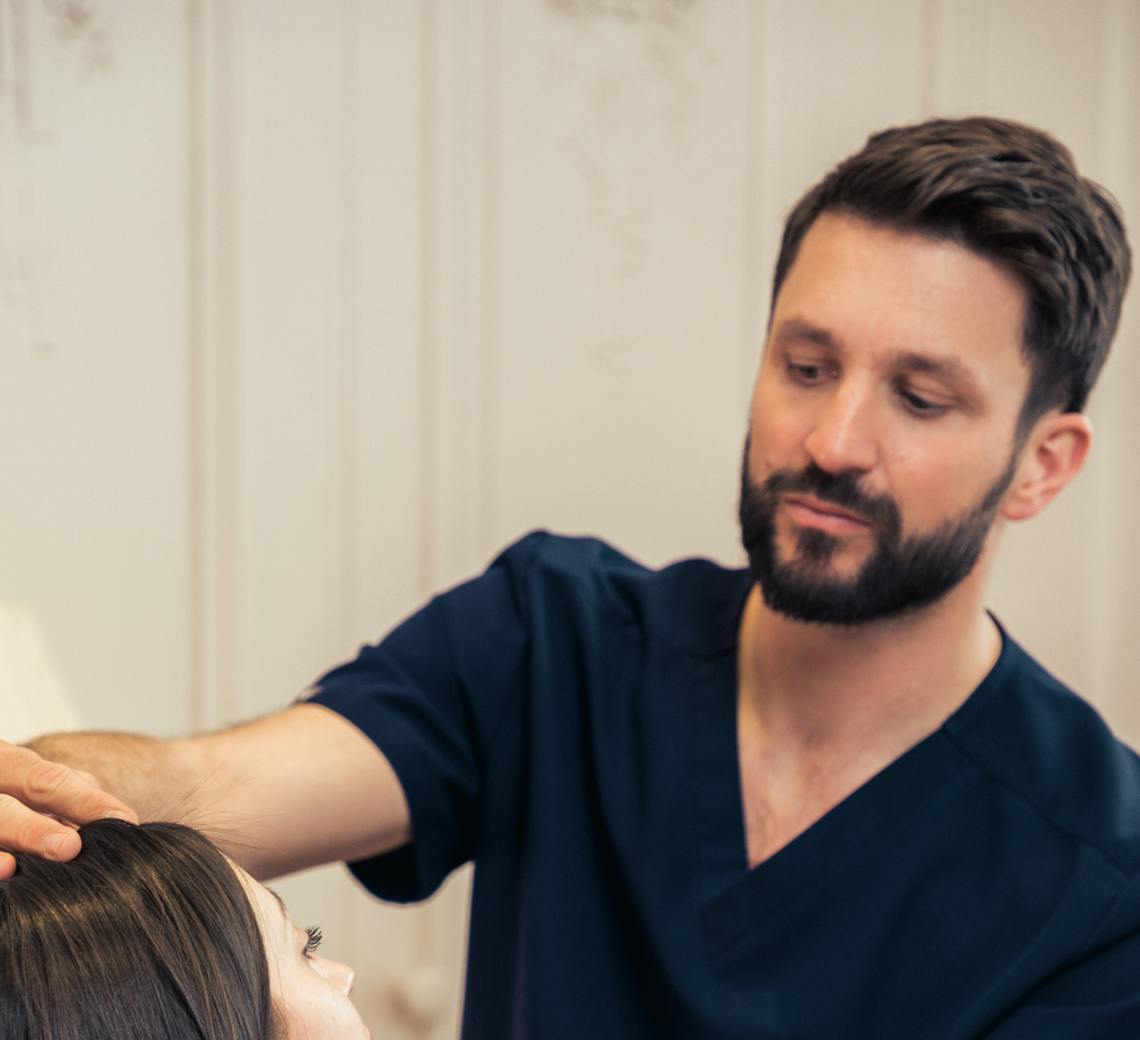 Chirurgien de chez Maison Yokō Lyon en consultation avec une patiente pour des injections. Il analyse son visage.