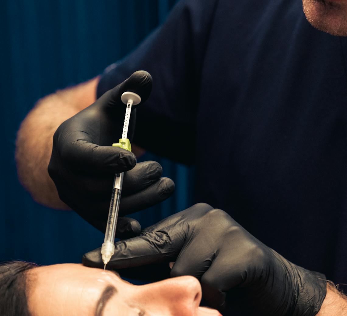 Praticien qui réalise des injections de Botox dans le visage d'une patiente.
