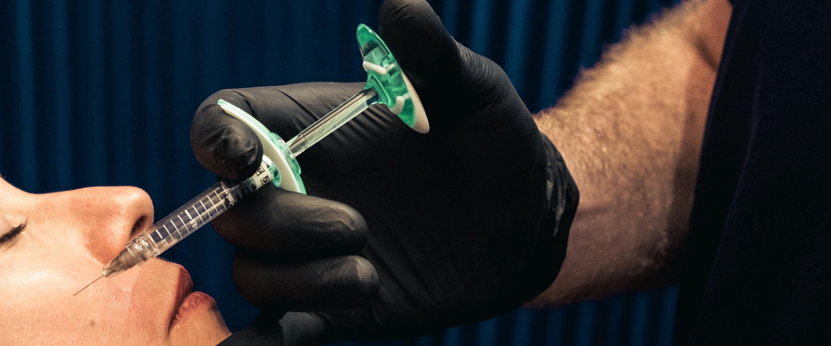 Chirurgien en train de réaliser une injection de Botox à l'aide d'une seringue dans le visage d'une patiente.