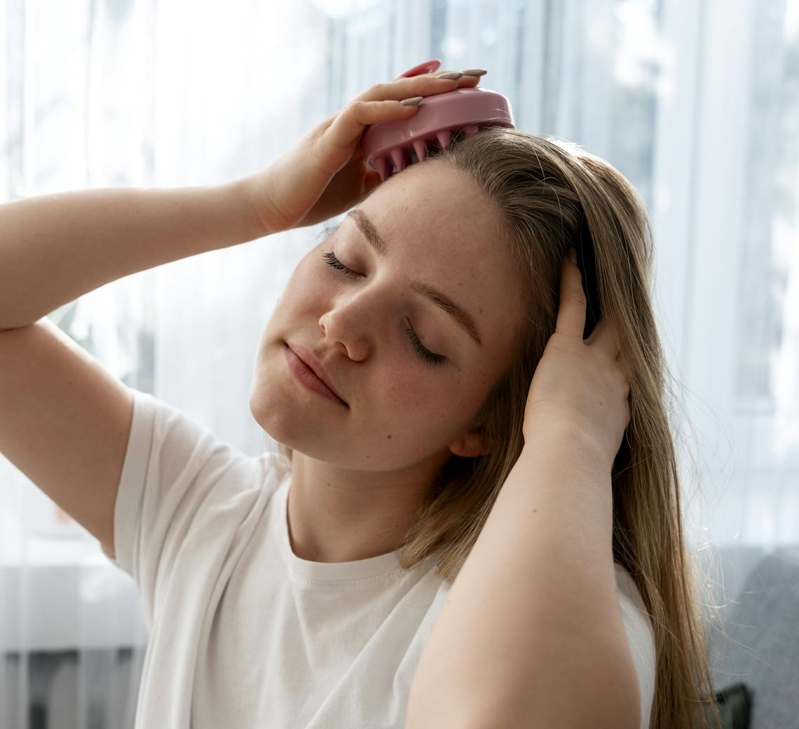 Femme qui se masse le cuir chevelu à la maison pour stimuler la circulation sanguine.