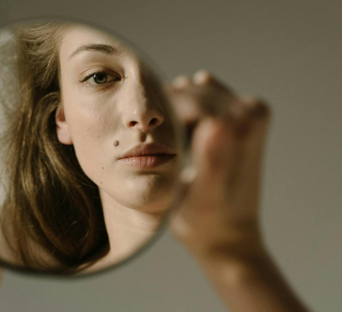 Jeune femme se regarde dans le miroir.
